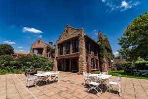 eine Terrasse mit Tischen und Stühlen vor einem Gebäude in der Unterkunft Gooderson Kloppenheim Country Estate in Machadodorp