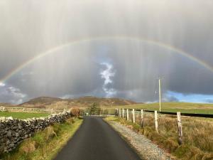 un arco iris en el cielo sobre un camino en Cleggan Farm Holiday Cottages en Cleggan