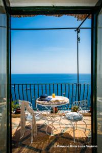 una mesa y sillas en un balcón con vistas al océano en Pensione Maria Luisa, en Positano