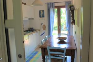 une cuisine avec une table et des chaises en bois, une table et une fenêtre dans l'établissement Casa Ortensia, à Tortolì