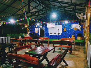 a restaurant with wooden tables and chairs and a screen at Star View Garden in Sai Yok