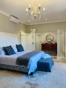 a large bedroom with a large bed and a chandelier at Bonne Chance Cottage in Paarl