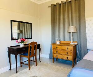 a bedroom with a desk and a bed and a mirror at Bonne Chance Cottage in Paarl