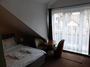 a bedroom with a bed and a table and a window at Apartamenty Donald in Krynica Morska