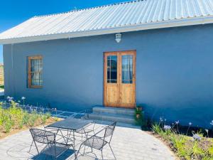 ein blaues Haus mit einem Tisch und Stühlen davor in der Unterkunft Bonne Chance Cottage in Paarl