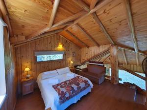 1 dormitorio en una cabaña de madera con 1 cama y 1 sofá en Cabaña Del Árbol en San Martín de los Andes