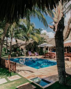a swimming pool with a palm tree and chairs at Paredon Surf House in El Paredón Buena Vista