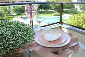 a table with a plate and a glass of wine on a balcony at CARNEIROS BEACH RESORT AP 311 E in Praia dos Carneiros