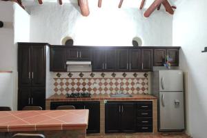 a kitchen with black cabinets and a refrigerator at Casa Ceiba de Mirabel-Barichara in Barichara
