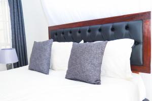 1 dormitorio con 1 cama con almohadas blancas en Sofitel 4 bedrooms maisonette Milimani, en Kisumu