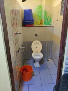 a small bathroom with a toilet and a bucket at Bedspace Living in Udupi
