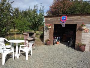 un patio con una mesa y sillas y un aro de baloncesto en Gites 10km de Granville, Hudimesnil, en Hudimesnil