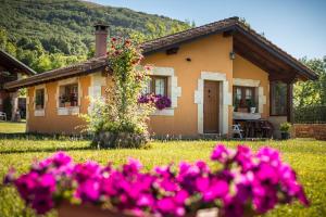 una casa con flores rosas delante de ella en CASUCAS LA GUARIZA ( Casa Marta) en Fontibre