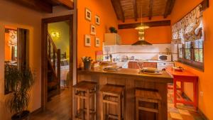a kitchen with orange walls and a counter with stools at CASUCAS LA GUARIZA ( Casa Marta) in Fontibre