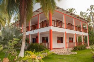 a building with palm trees in front of it at Playa Mareygua Hostal in Buritaca