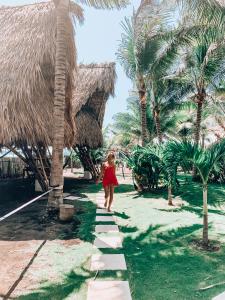 a woman walking down a path in front of a resort at Paredon Surf House in El Paredón Buena Vista