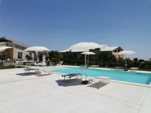 a swimming pool with umbrellas and chairs next to a pool at Casa Sbrizza in Rosolini