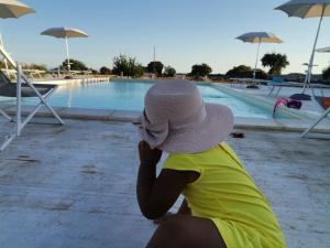 a woman in a hat sitting next to a swimming pool at Casa Sbrizza in Rosolini