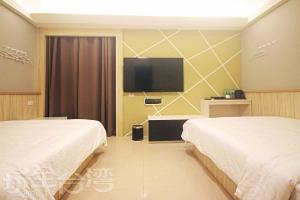 a hotel room with two beds and a flat screen tv at 樂客2館 in Hsia-shih +4 photos