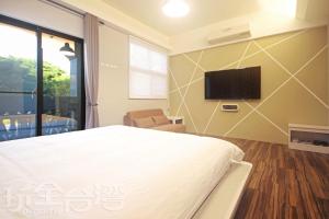 a bedroom with a bed and a tv on a wall at 樂客2館 in Hsia-shih
