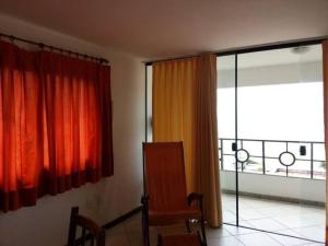 a room with orange curtains and a chair and a balcony at PontaNegra Ponta do Sol 5D Luciene Vista deslumbrante para o mar in Natal