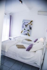 a bedroom with two beds with white sheets and purple pillows at Hôtel Le Méditerranée in Hyères