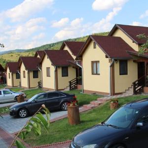 a row of houses with cars parked in front of them at Manó Kulcsosházak in Praid
