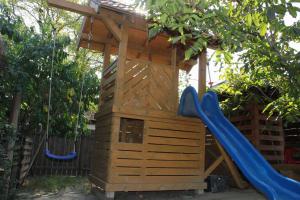 a wooden playground with a slide and a swing at Cerdacul cu Stuf in Sfântu Gheorghe