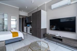 1 dormitorio con 1 cama y TV grande en Top Floor Menlyn Maine studio apartment with Stunning Views & No Load Shedding en Pretoria