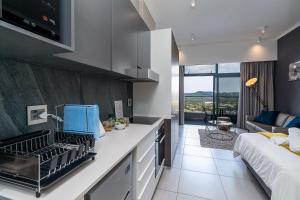 uma cozinha com um lavatório e um sofá num quarto em Top Floor Menlyn Maine studio apartment with Stunning Views & No Load Shedding em Pretoria