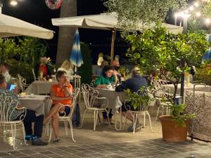 ludzie siedzący przy stolikach w restauracji na świeżym powietrzu w nocy w obiekcie Albergo Bellavista w mieście Limone sul Garda