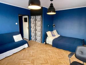 um quarto com paredes azuis, uma cama e um sofá em Super Apartament BLUE Ścisłe Centrum Dwie Linie Metra Netflix WiFi 300 Mbs Panorama Miasta em Varsóvia