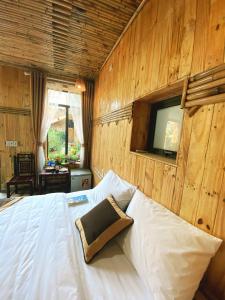 a bedroom with a white bed with a wooden wall at Trang An Moon Garden Homestay in Ninh Binh