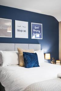 a bedroom with a blue wall and a bed with pillows at Inspire Homes - Joe's Cottage in Southam