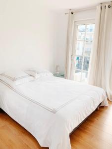 ein weißes Bett in einem weißen Schlafzimmer mit einem Fenster in der Unterkunft Appartement 6 pers. à Disneyland Paris in Chessy