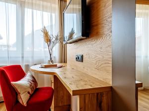 Habitación con escritorio y silla roja. en Stadthotel EGGERBRÄU, en Imst