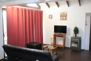 sala de estar con cortinas rojas y TV en Cabañas Kakanchik en Vicuña