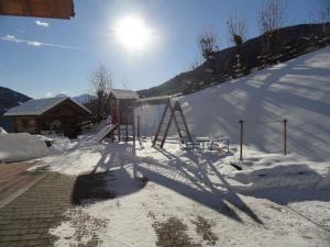 a snow covered slope with a playground in front of a building at Pirchnerhof in San Lorenzo di Sebato