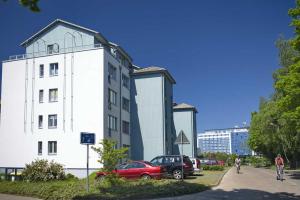 ein weißes Gebäude mit einem daneben geparkten roten Auto in der Unterkunft Zinnowitz Haus Zur Düne in Zinnowitz