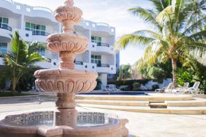 a fountain in front of a building with palm trees at Costa Madero Resort in Los Ayala