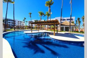 una gran piscina con palmeras y un edificio en DEPARTAMENTO EN PLANTA BAJA CON TERRAZA en Mazatlán