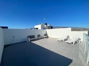 un patio con sillas blancas y una pared blanca en New and cosy apartment - 4 min walk from the beach - La Tejita - El Medano en Granadilla de Abona