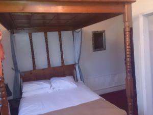 1 dormitorio con cama con dosel y sábanas blancas en Rose & Crown Hotel, en Bainbridge