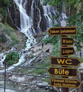 a bunch of signs in front of a waterfall at Basturk Dinlenme Tesisi in Büyükçakır