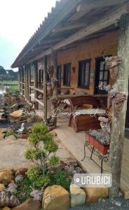 a wooden house with a bench on a deck at Pousada Nó de Pinho in Urubici