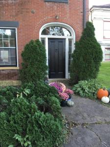 uma porta da frente de uma casa com abóboras e flores em The Federal House em Galena