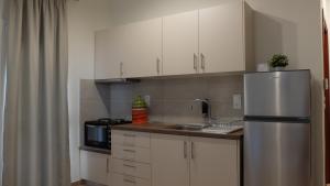 a kitchen with white cabinets and a stainless steel refrigerator at Elata Apartments in Limenas