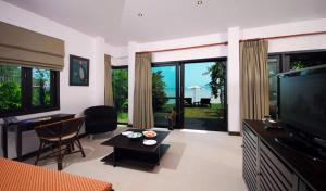 a living room with a flat screen tv and a couch at Cinnamon Beach Villas in Lamai