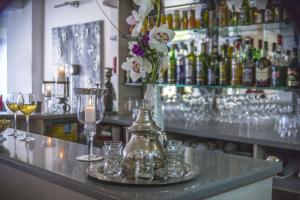 a bar with glasses and a vase of flowers on a counter at Hôtel Le Méditerranée in Hyères