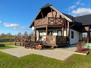 ein großes Holzhaus mit einer Veranda und einem Balkon in der Unterkunft Mazurska Osada nad jeziorem Orzysz in Skomack Wielki